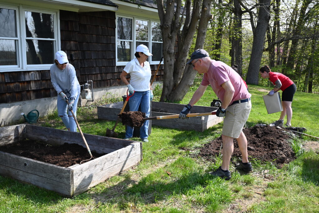 Four volunteers from Keller Williams work on freshening planting boxes on the Saco campus.